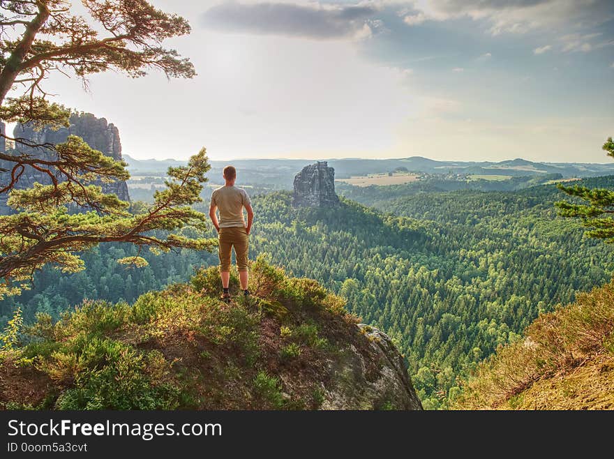 Man hiker on mountain top hiking or climbing. Looking and enjoying inspirational view into landscape