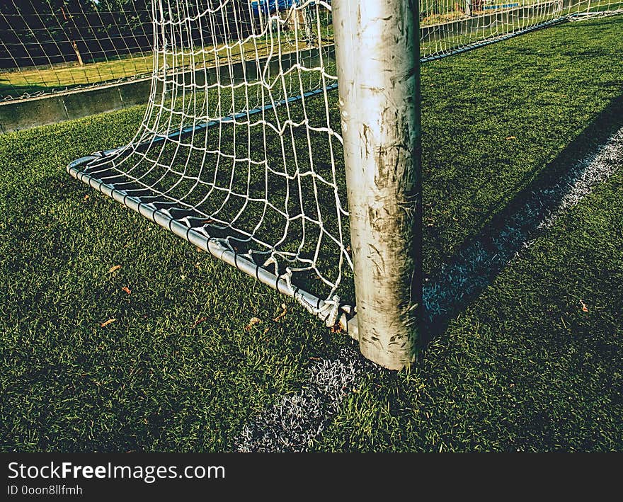 Goal with net and green playing field. Closeup view to football training playground