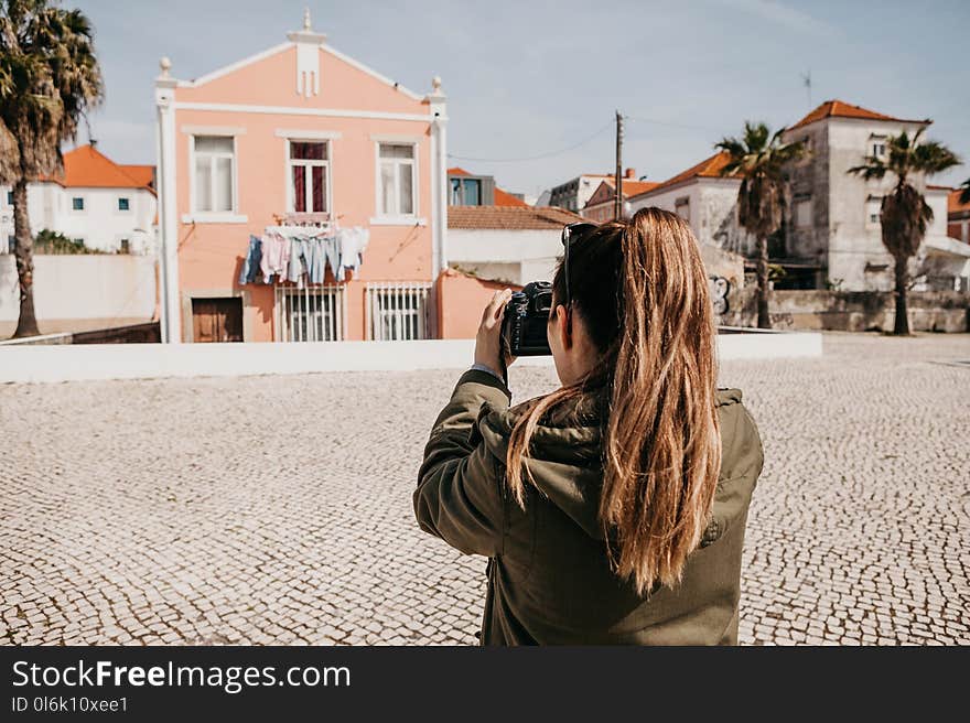 A street photographer or a young woman takes pictures of authentic houses in Lisbon in Portugal. A professional photographer or tourist taking pictures for memory.