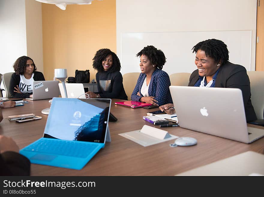 Group of People Talking to Each Other in Front of Brown Wooden Table