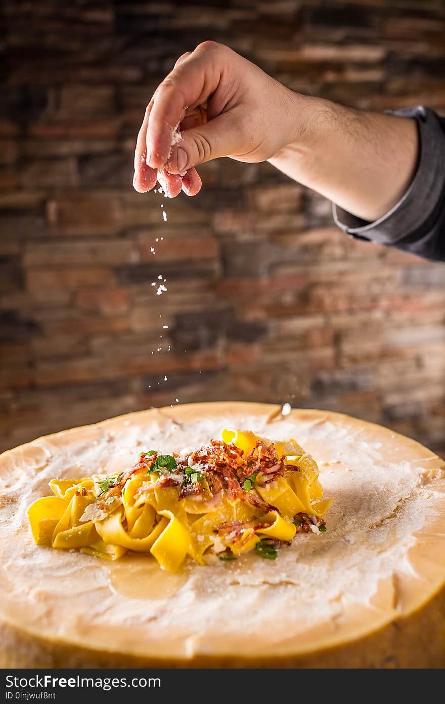 Chef in restaurant exclusively preparing italian pasta pappardelle on a block cheese parmesan. Chef in restaurant exclusively preparing italian pasta pappardelle on a block cheese parmesan.