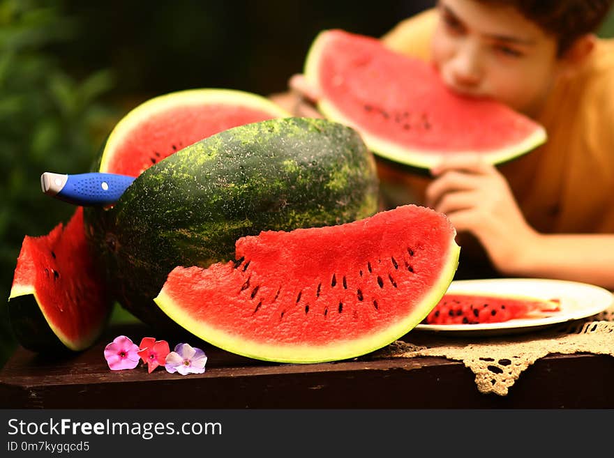 Teenager boy with cut water melon close up photo on green garden background