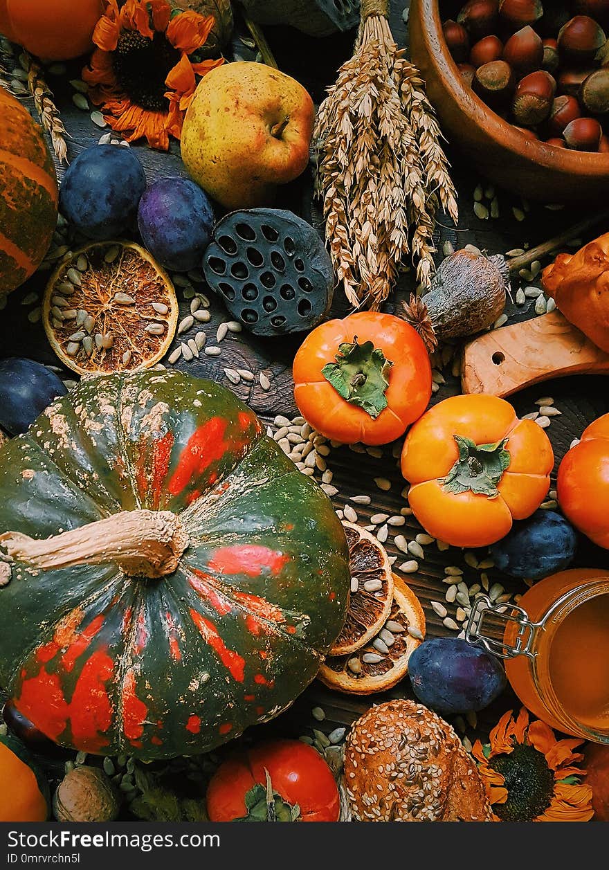 Autumn still life, Harvest, Pumpkins, persimmon, plums, nuts, wheat, homemade bread on dark wooden background, Rustic life