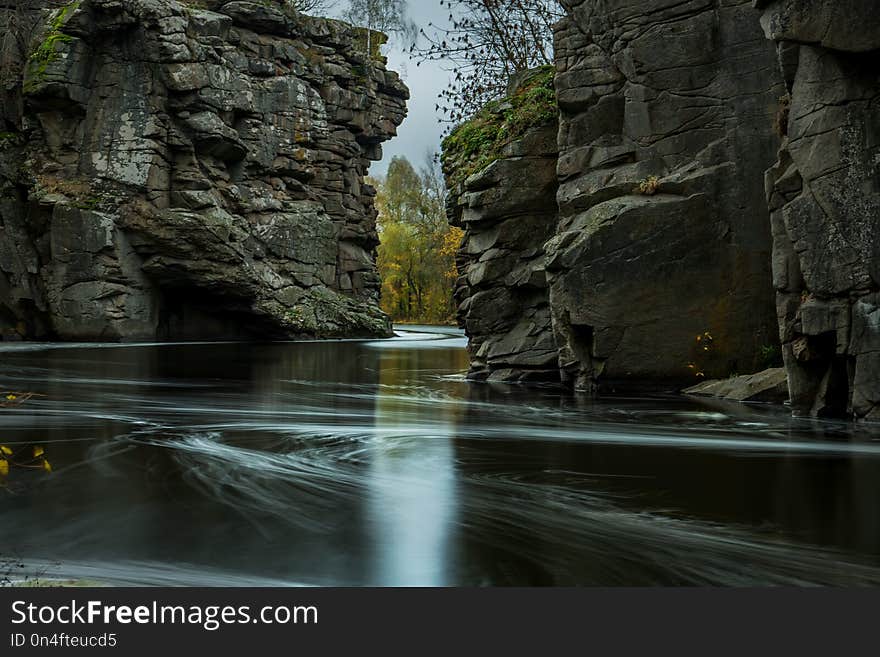 The river is fast with stony shores and autumnal yellow trees. Autumn view of the river.