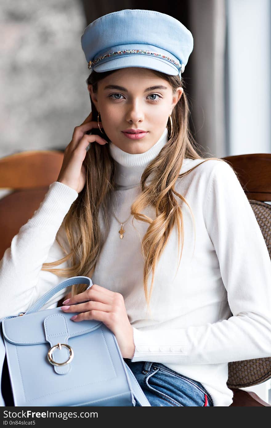 Beautiful young girl in red boots, fashionable clothes and blue colored cap. The girl in the restaurant. Trend clothing. Without filters. Natural color. Beautiful young girl in red boots, fashionable clothes and blue colored cap. The girl in the restaurant. Trend clothing. Without filters. Natural color.