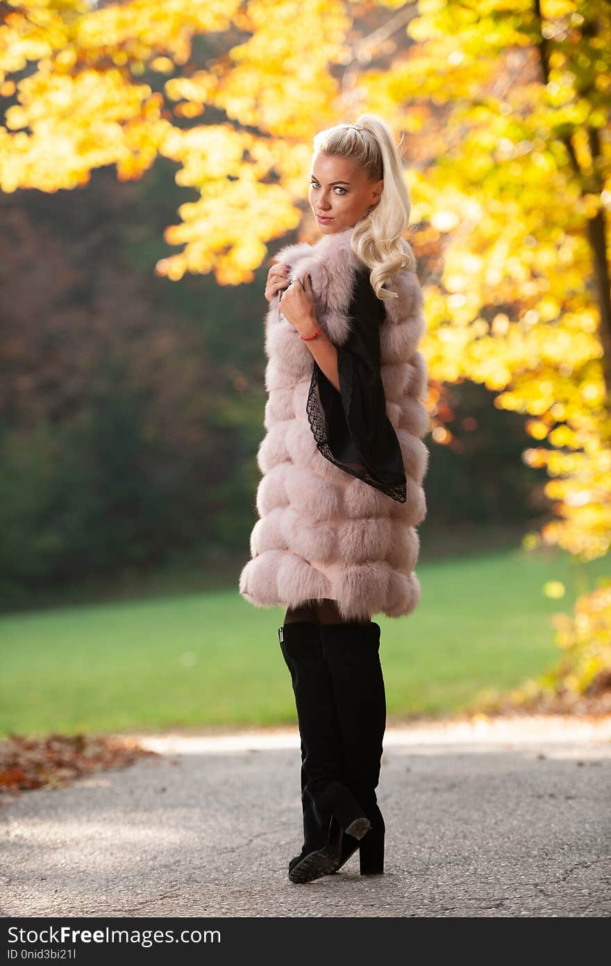 Beautiful stylish woman pose in park in early autumn .