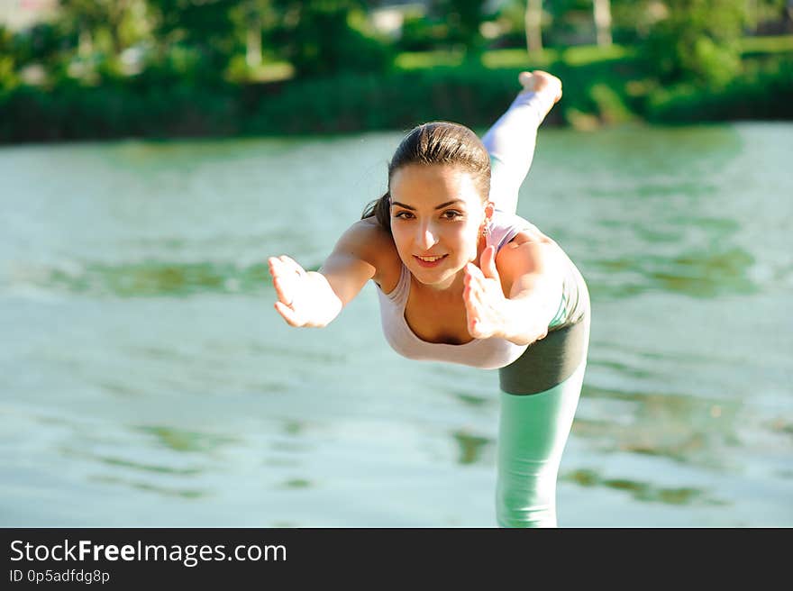 Beautiful young woman meditating in yoga pose at a mountain stream.