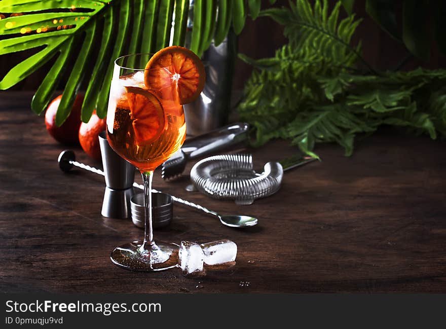 Aperol spritz cocktail in big wine glass with orange slices, summer cool fresh alcoholic cold beverage. Wooden bar counter