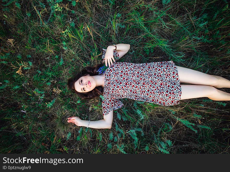 Top view Portrait of a beautiful young woman or girl lying on green meadow field watching to the sky and enjoying nature summer evening. Calm and harmony. Nature rest. Flat lay. Copy space