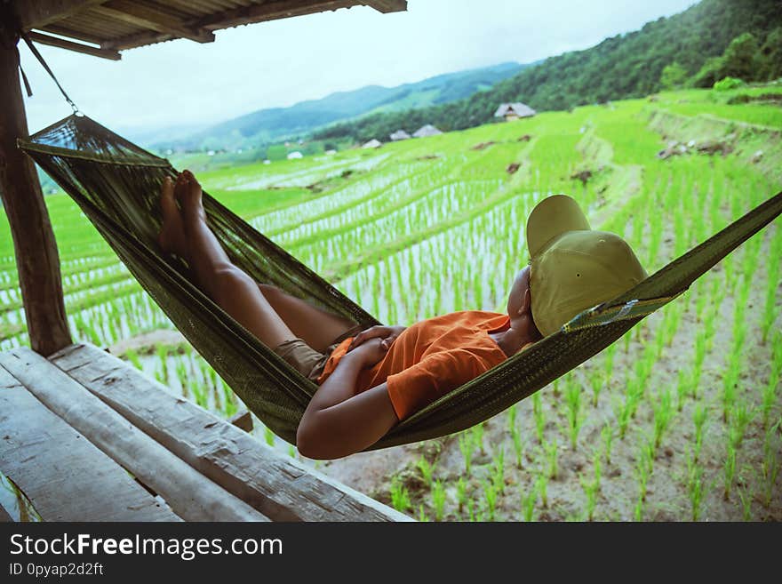 Asian woman travel nature. Travel relax. Relax in the hammock the balcony of the resort. View of the field on the Moutain in