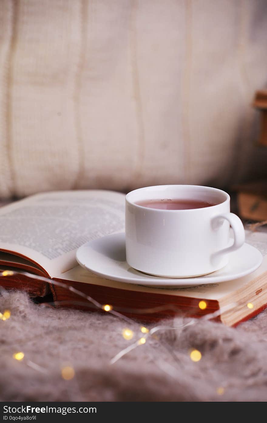 Hot tea and book with woolan plaid on wood background - seasonal relax concept. Autumn winter weekend still life background, cozy