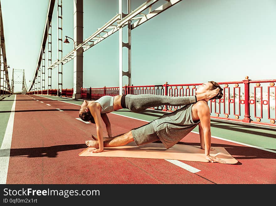 Harmony with nature. Couple of young yogis doing their stretching workout outdoors in fine summer weather. Harmony with nature. Couple of young yogis doing their stretching workout outdoors in fine summer weather