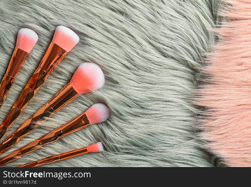 Set of professional makeup brushes on furry fabric, flat lay. Space for text