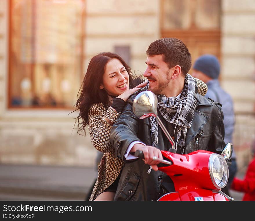 Happy young couple on scooter bike in autumn city together