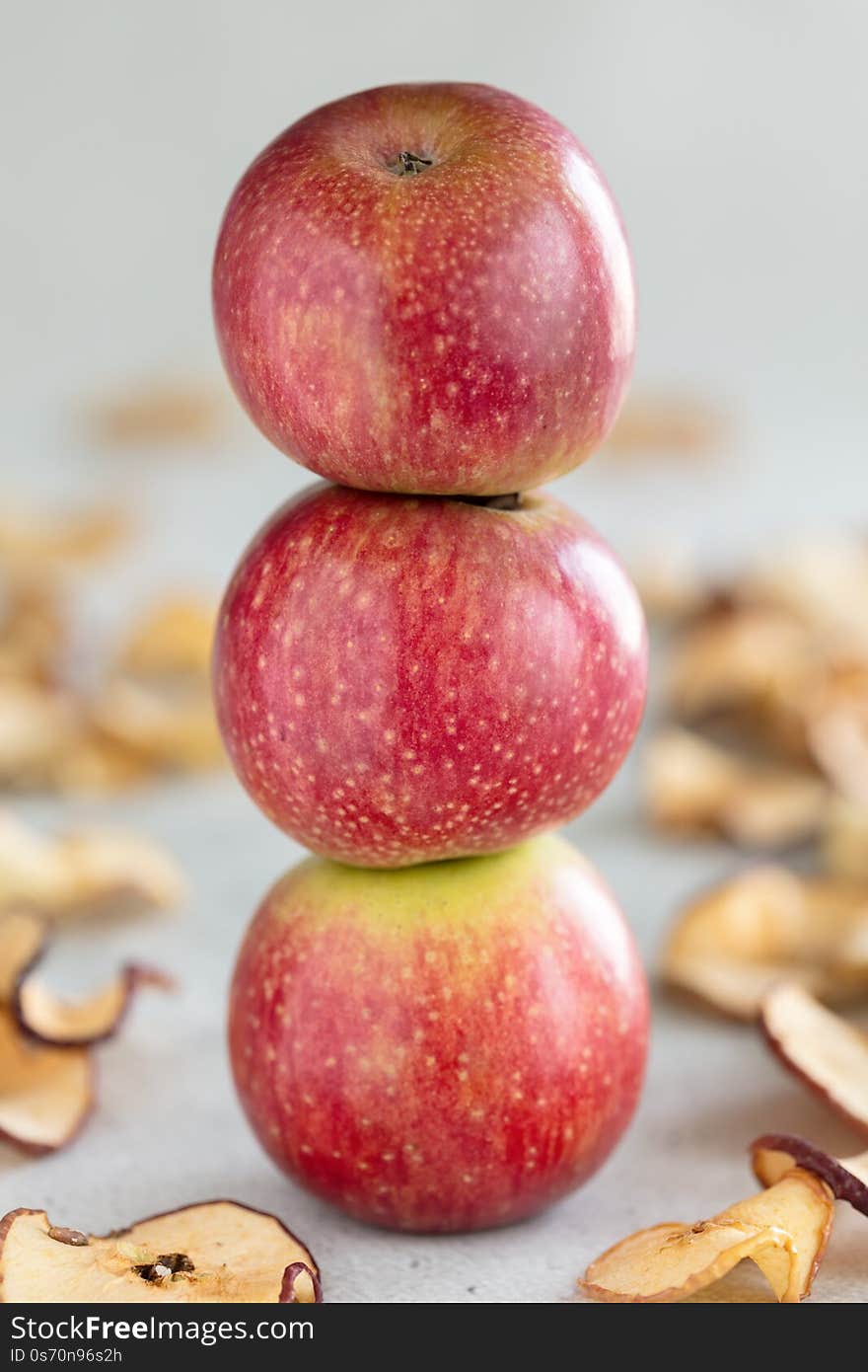 Stack of three fresh apples and Sun dried apple chips as a healthy snack, vertical composition