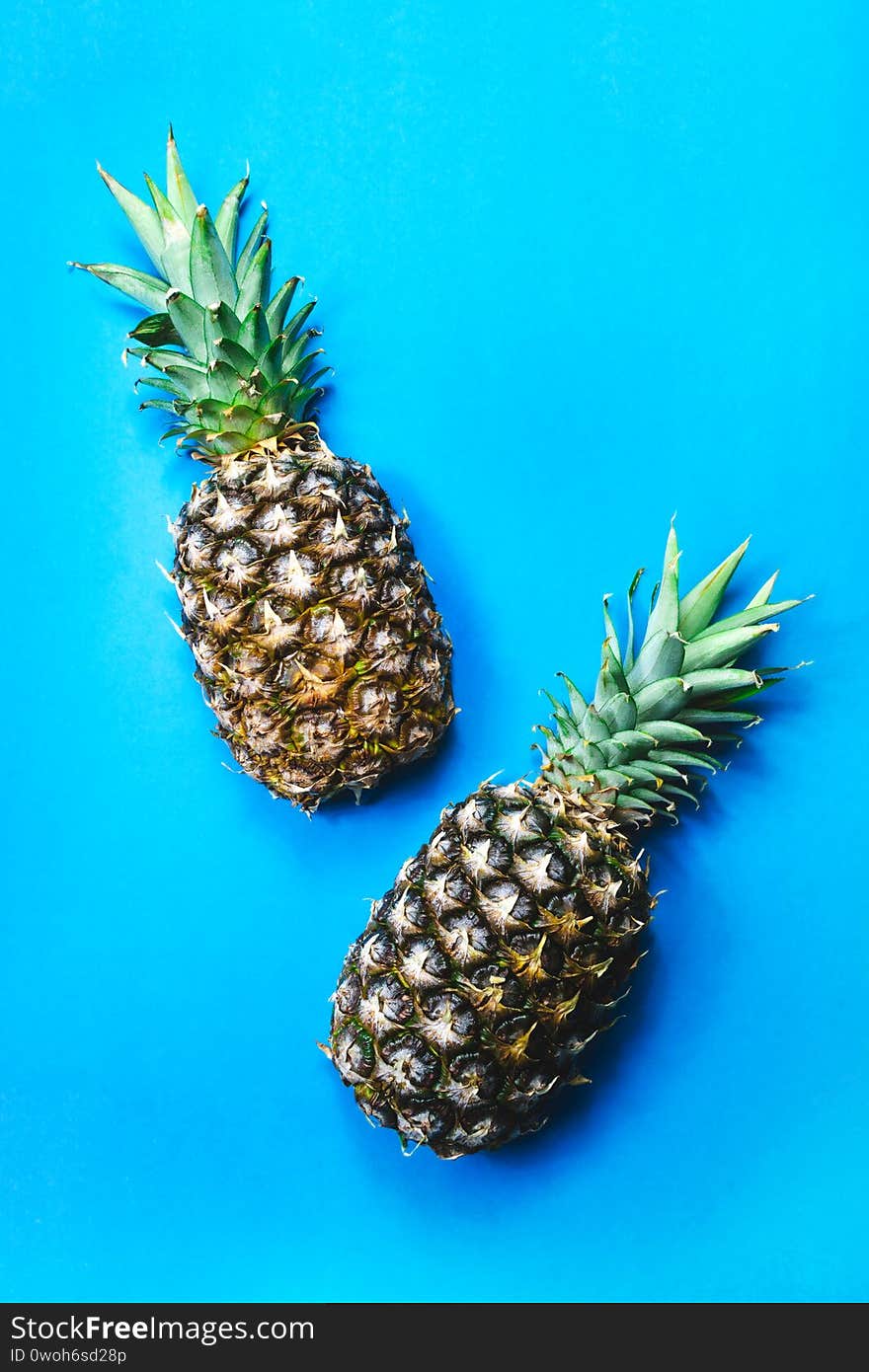 Two green pineapple cut in half on blue summer top view background. Sweet food art flat lay composition. Healthy food, diet, fresh juicy tropical fruit creative concept. Poster, banner design template. Two green pineapple cut in half on blue summer top view background. Sweet food art flat lay composition. Healthy food, diet, fresh juicy tropical fruit creative concept. Poster, banner design template