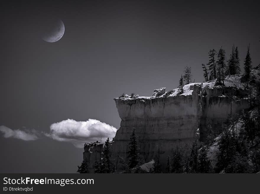 Black and white, fine art scene of a half moon setting at night over a rock cliff in Bryce Canyon National Park, Utah. Black and white, fine art scene of a half moon setting at night over a rock cliff in Bryce Canyon National Park, Utah.