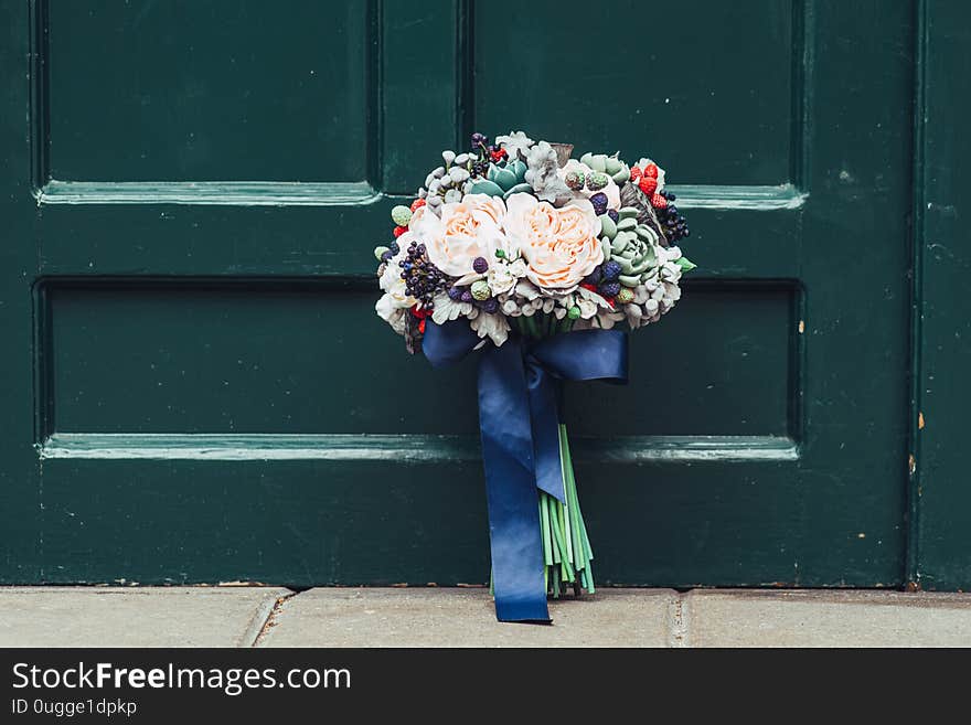 Handmade flowers made from Japanese polymer clay. They look like a real wedding bouquet. Against the background of a green wooden door.