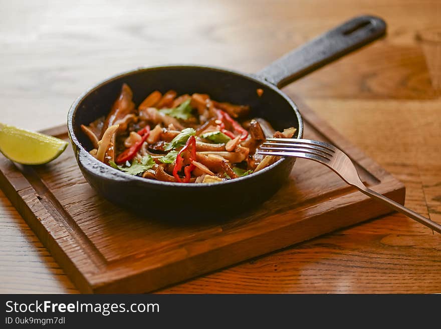 Pork ear snack in a pan. Spicy meat grilled pork served in a frying pan on rustic wooden cutting board.