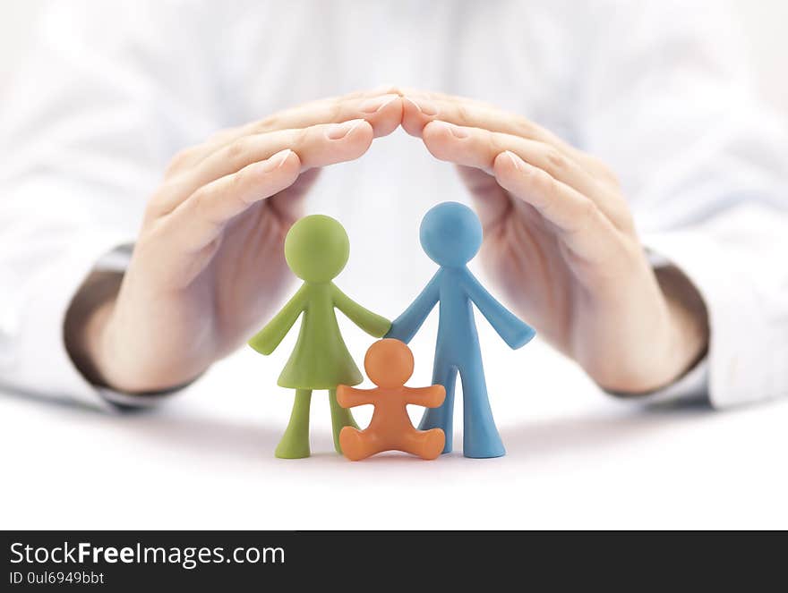 Family insurance concept with small colorful family figurines covered by hands