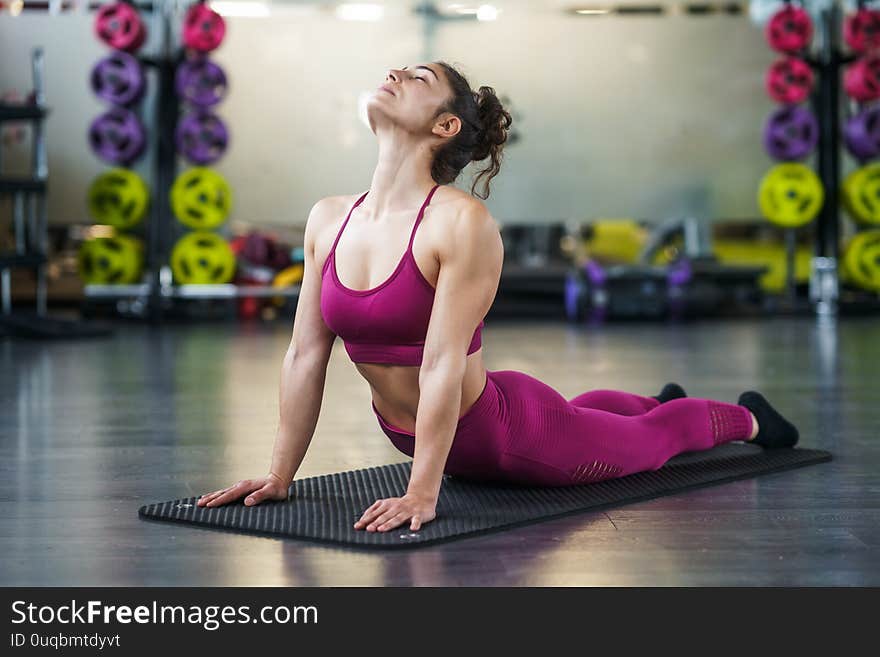 Young woman Doing Stretching Exercises on a yoga mat at the Gym