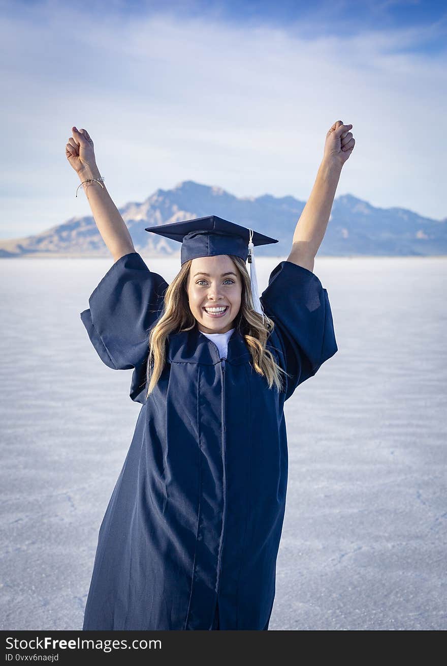 Cute Young woman in her graduation cap and gown showing excitement after graduating. Beautiful girl showing real emotion after finishing her degree