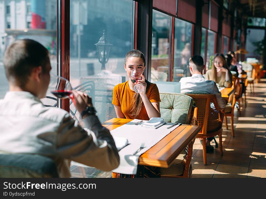 A young couple drinking wine in a restaurant near the window.