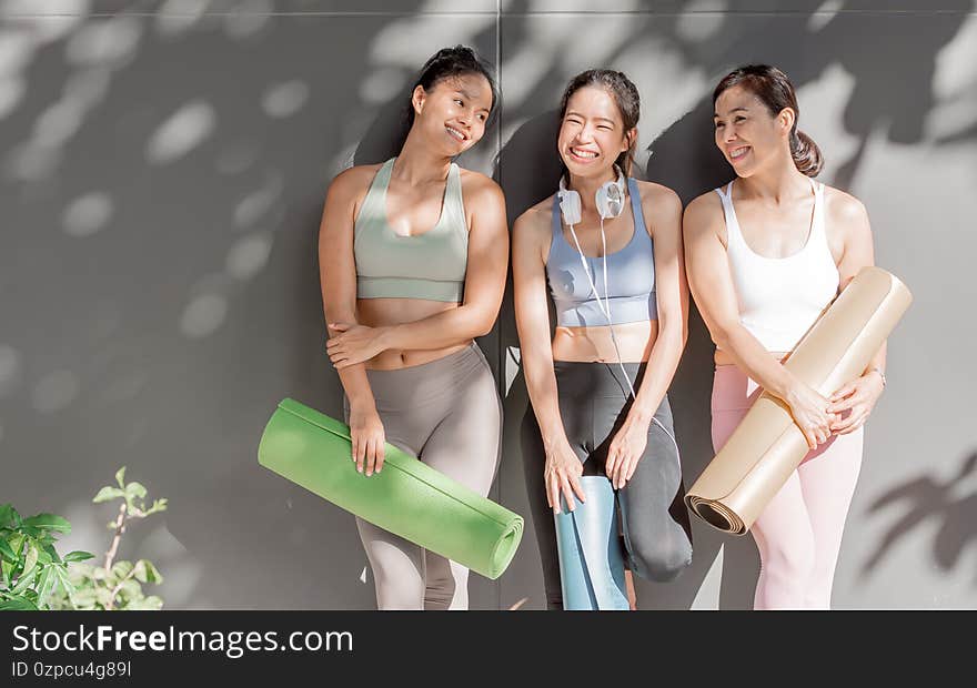 Asian women wearing sport bra, talking and laughing together after doing exercise in yoga class at gym. Sport, Friendship and Healthy Concept. Asian women wearing sport bra, talking and laughing together after doing exercise in yoga class at gym. Sport, Friendship and Healthy Concept