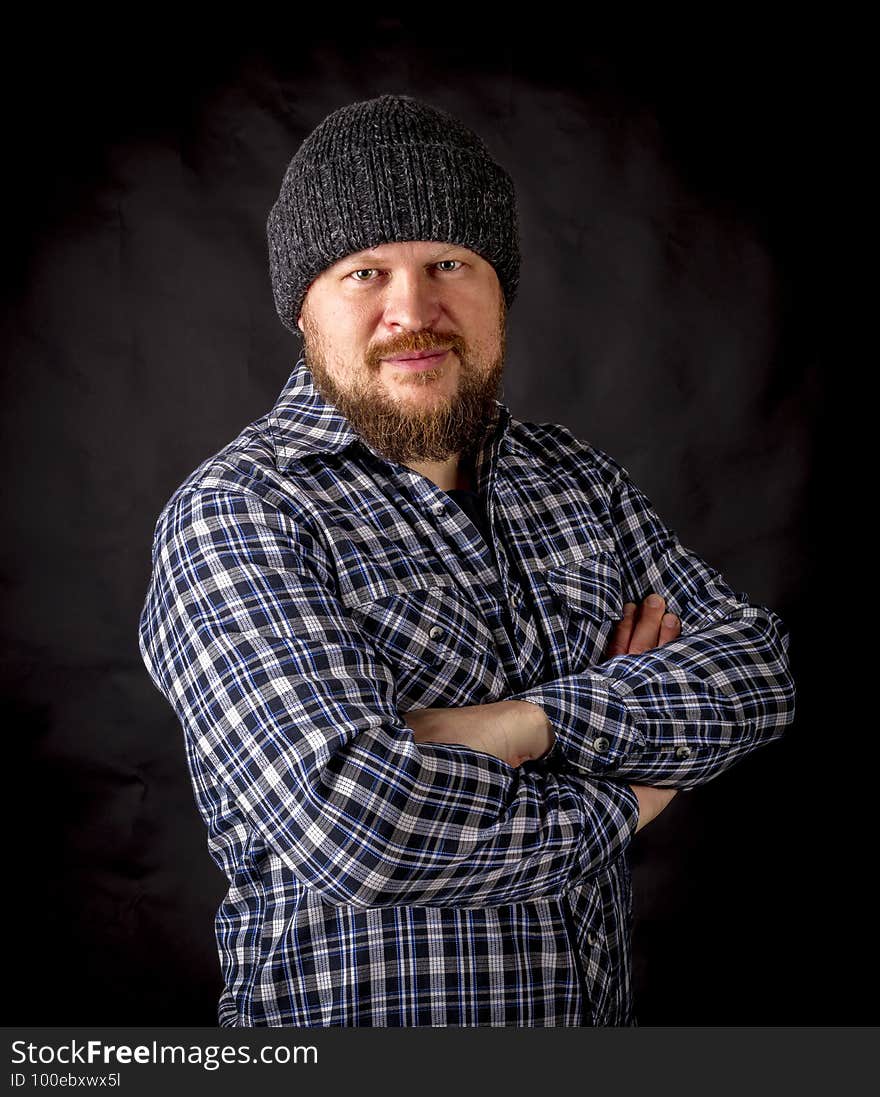 Solid bearded man in a wool cap portrait on black background