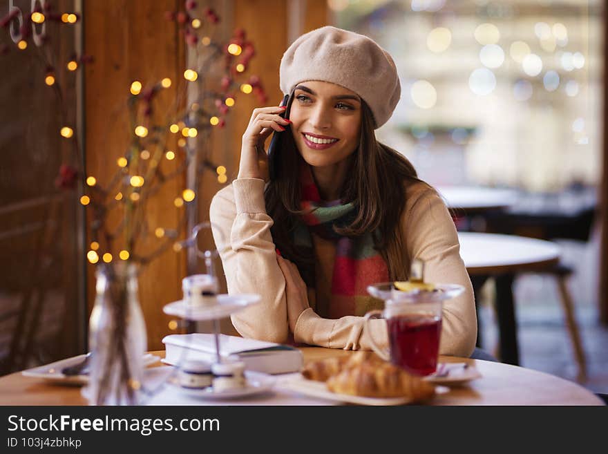 Shot of cheerful smiling beautiful woman talking with somebody on her mobile phone while sitting in the cafe. Shot of cheerful smiling beautiful woman talking with somebody on her mobile phone while sitting in the cafe