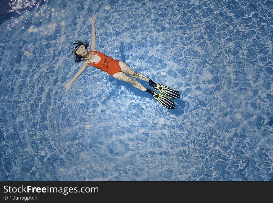 Aerial top view of lifestyle young woman in red swimwear which she is a lying on the poolside,which she is a relax time with