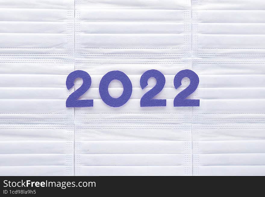 Violet felt new year numbers 2022 on white medical masks background. Inspired by trendy very peri color of the last year 2022. Place for your text here