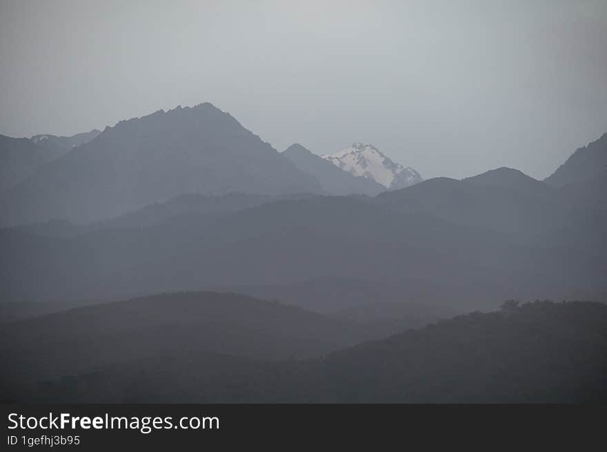 Landscape of the Trans-Ili Alatau mountains on an early cloudy morning in thick morning fog, haze