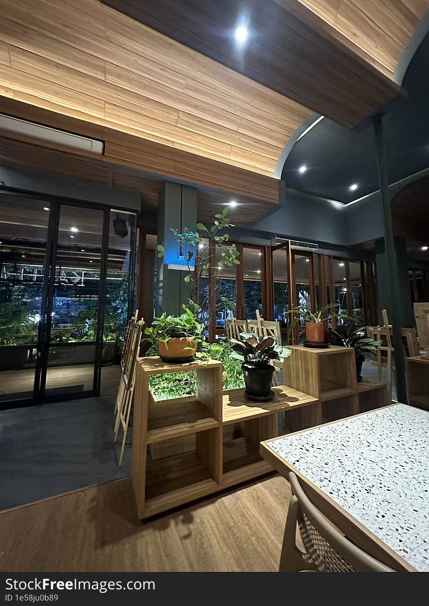 A neatly arranged wooden shelf in a restaurant. The shelf is placed in the middle of the restaurant to enhance the aesthetics. On top of it, plastic pots with beautiful minimalist plants are placed. A neatly arranged wooden shelf in a restaurant. The shelf is placed in the middle of the restaurant to enhance the aesthetics. On top of it, plastic pots with beautiful minimalist plants are placed.