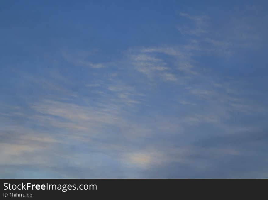 Cirrus and cumulus clouds in the dark blue sky on an early winter morning.