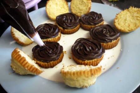 Adding brown frosting as a hamburger patty to cupcakes.