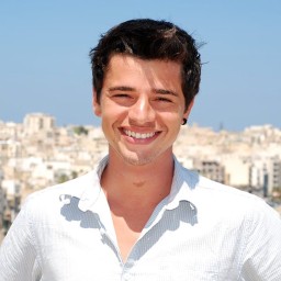 Portrait photograph of me smiling with a blurred background.