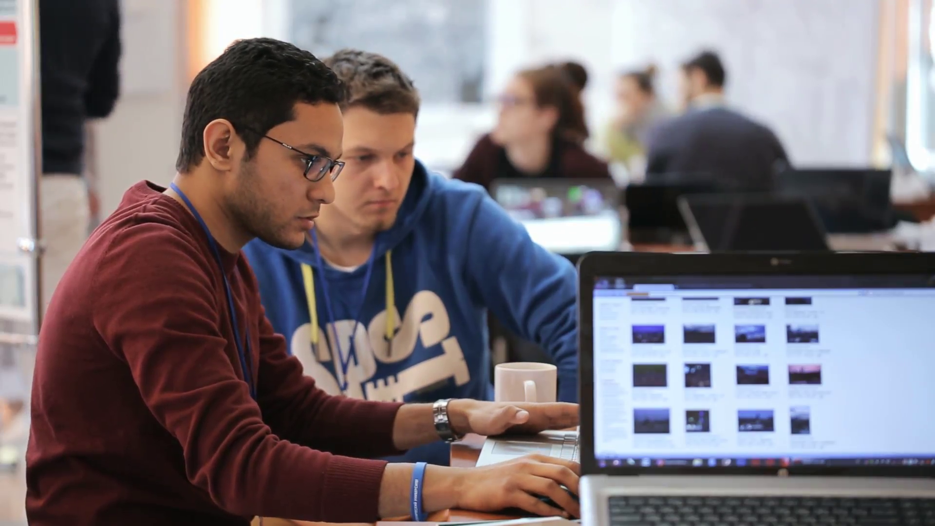 Two men working at the computer attentively, and discussing ...