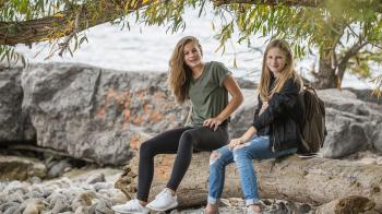 2 Women Sitting on Rock during Daytime