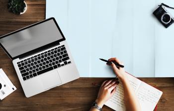 Person Holding Pen Near Macbook Pro