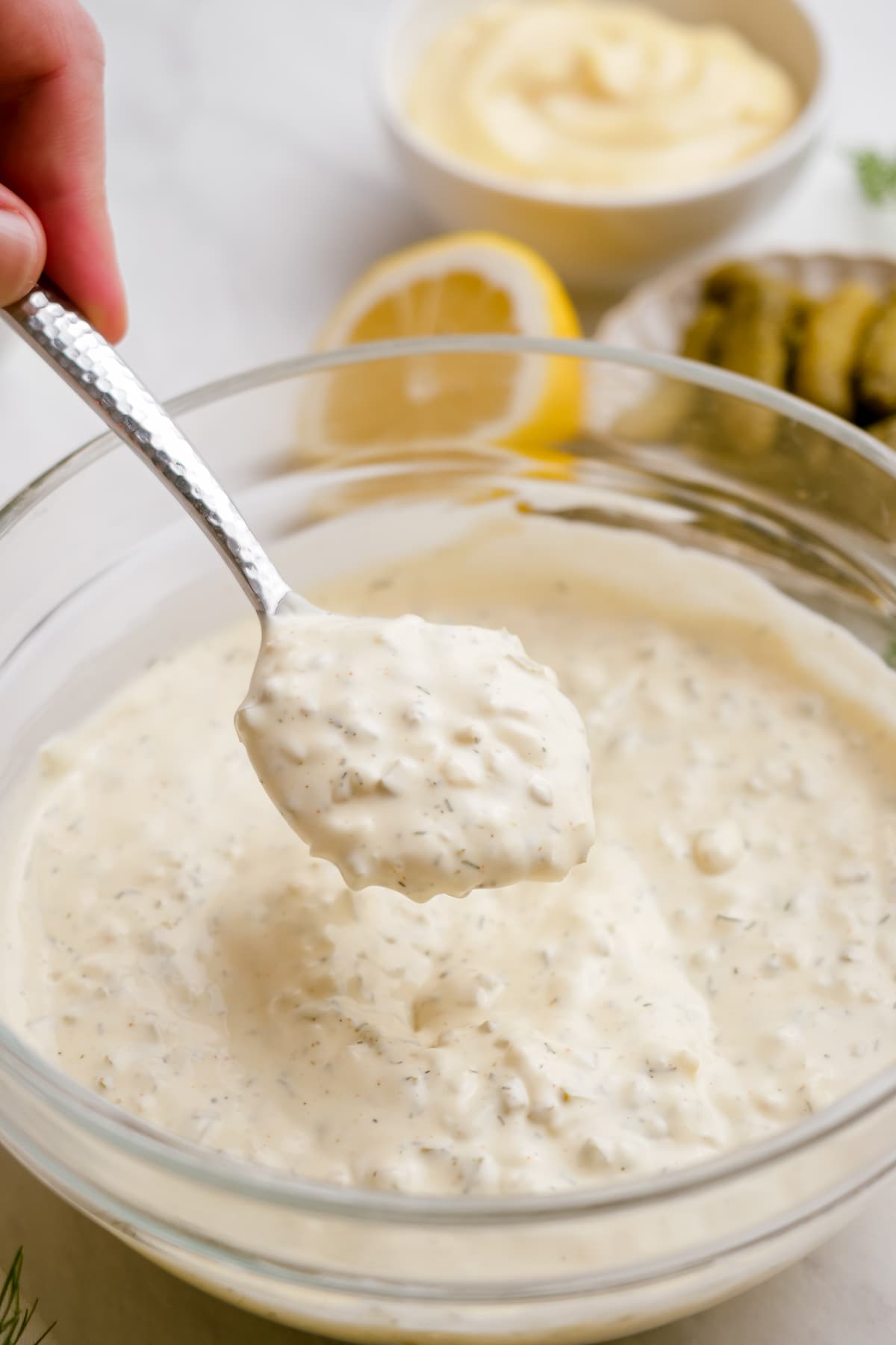 woman's hand spooning out tartar sauce from bowl