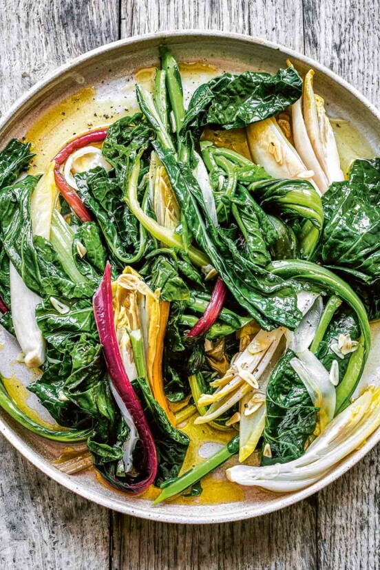 A white plate filled with horta, or boiled greens with garlic.