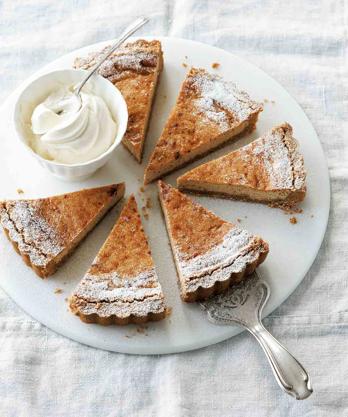 A round white plate with six slices of eggnog pie and a dish of whipped cream.