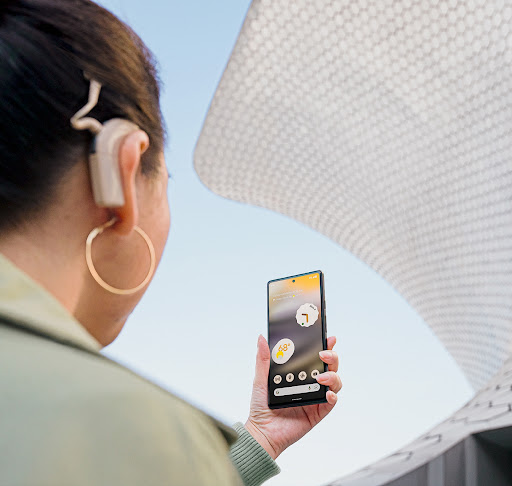 Person with a cochlear implant holds Android phone in front of them.