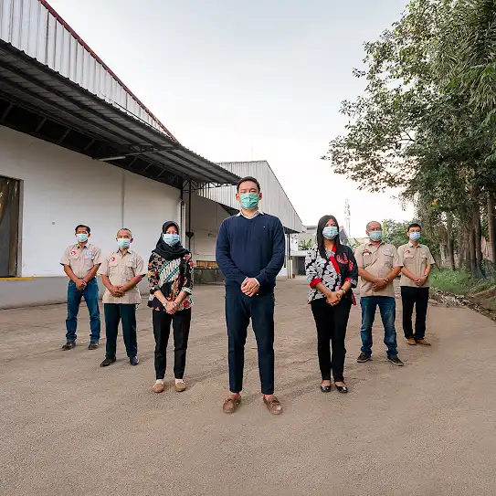 Sebuah tim berdiri bersama di luar fasilitas manufaktur mereka