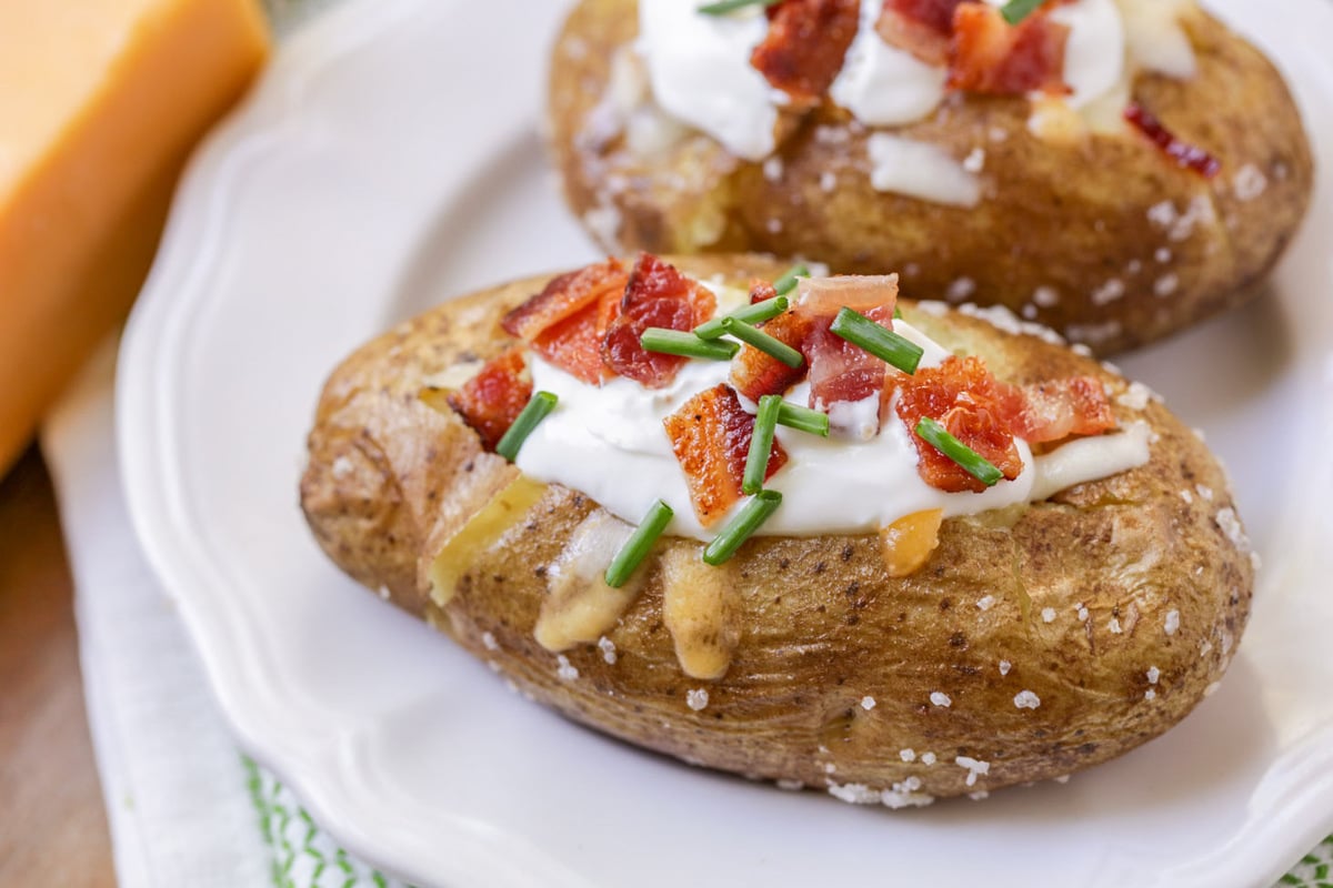 Salted baked potatoes topped with sour cream, bacon, and chives.