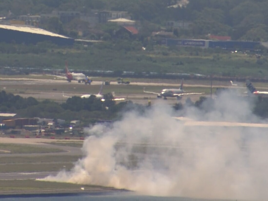 Grassfire at Sydney Airport after Qantas flight QF520 lands, plans in background