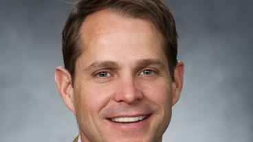 Headshot image of Shad Morris smiling in a suit and tie.