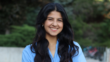 Román smiles confidently at the camera with her arms crossed.