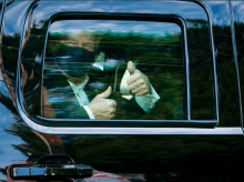 a man wearing a mask is giving a thumbs up from the window of a car